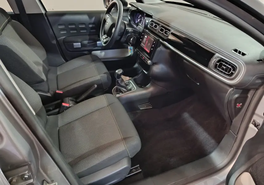Intérieur avant droit de la Citroën C3 gris foncé 2024, avec tableau de bord tactile et sièges tissu noirs.