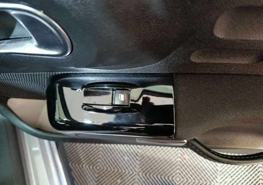 Commande de lève-vitre électrique côté conducteur sur panneau de porte intérieure d'une Citroën C3 gris foncé 2024.