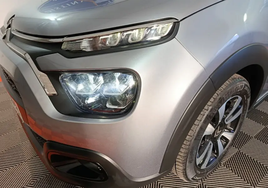 Gros plan sur l'avant droit gris foncé d'une Citroën C3 2024, mettant en valeur ses phares LED et sa roue.