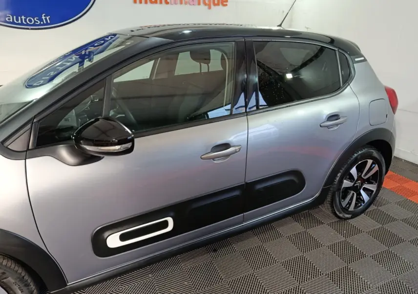 Profil côté gauche d'une Citroën C3 gris foncé 2024 avec protections latérales noires et jantes stylisées.