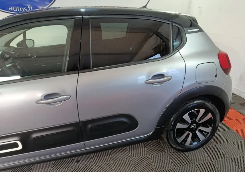 Vue latérale droite d'une Citroën C3 gris foncé avec protections de porte noires et jantes stylisées.