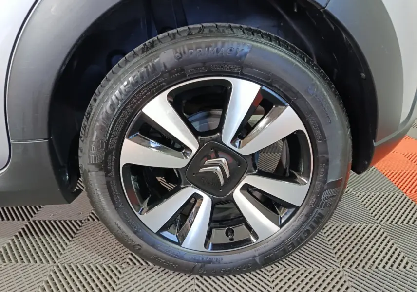 Gros plan sur la roue avant gauche de la Citroën C3 gris foncé avec jante alliage bicolore et logo central distinctif.