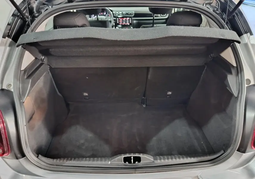 Coffre ouvert vu de l'arrière d'une Citroën C3 gris foncé, montrant l'espace de chargement et l'intérieur du véhicule.