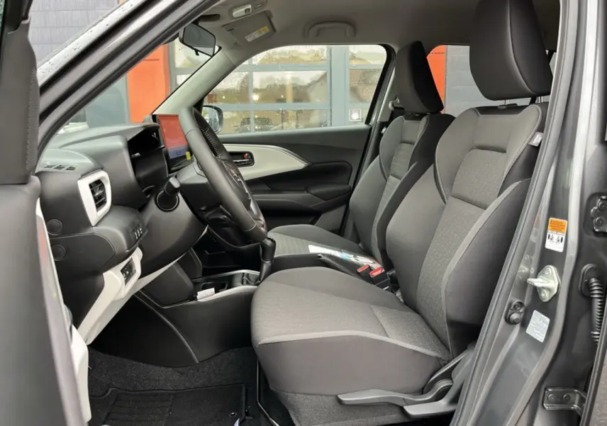 Vue intérieure côté conducteur de la Suzuki Swift 2025 gris minéral, sièges tissu gris et tableau de bord moderne.