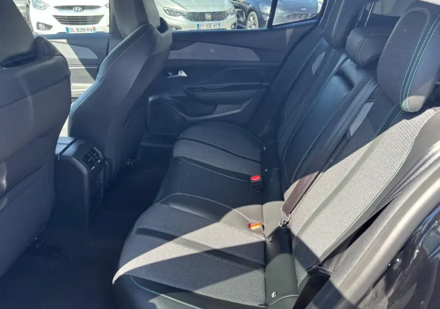 Vue latérale droite des sièges arrière noirs en cuir et tissu du Peugeot 408 Hybrid 2025 avec ceinture de sécurité et accoudoir central.