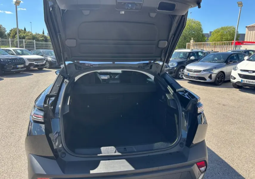 Coffre ouvert vu de l'arrière d'une Peugeot 408 Hybrid 136 e-DCS6 Allure noire, avec hayon relevé en extérieur.