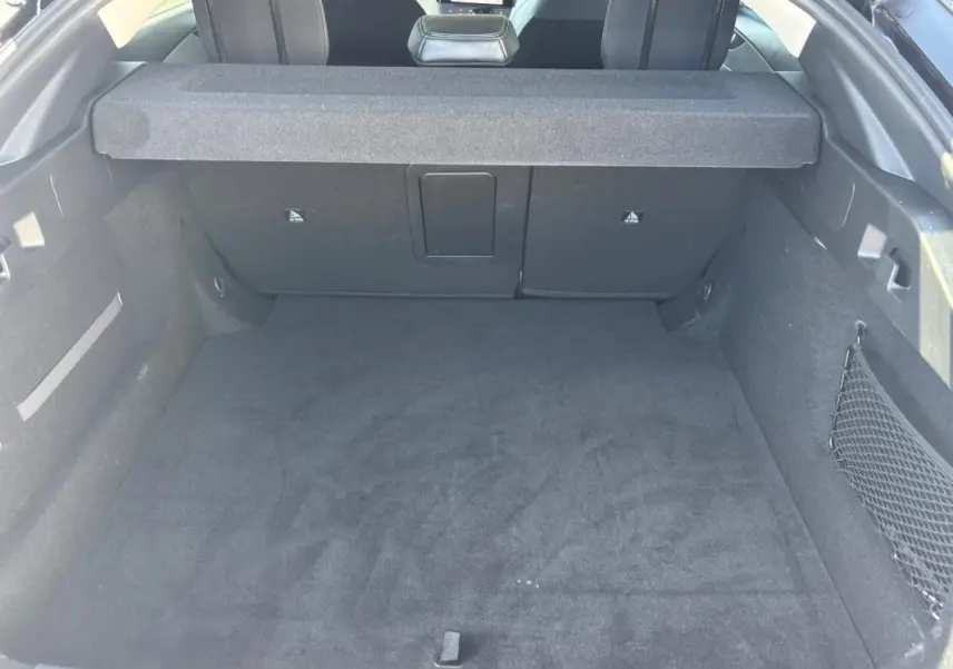 Coffre spacieux noir de la Peugeot 408 Hybrid 136 e-DCS6 Allure vu de l'arrière avec cache-bagages en place.