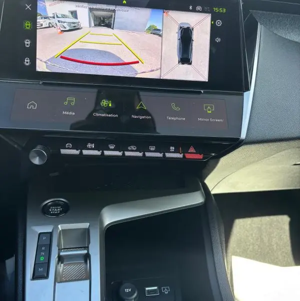 Vue intérieure du tableau de bord de la Peugeot 408 Hybrid 136 e-DCS6 Allure 2025, écran tactile avec caméra de recul et console centrale noire.