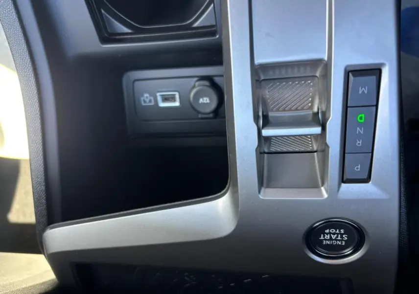 Gros plan sur la console centrale grise du Peugeot 408 Hybrid noir, montrant levier de vitesses électronique et bouton start/stop.