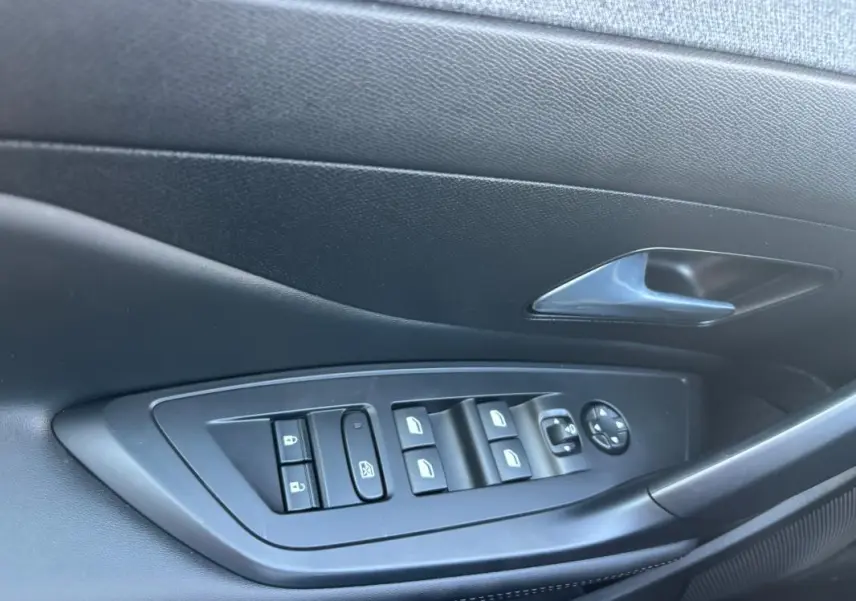 Gros plan sur la commande des vitres et rétroviseurs côté conducteur de la Peugeot 408 Hybrid noire, finition Allure 2025.