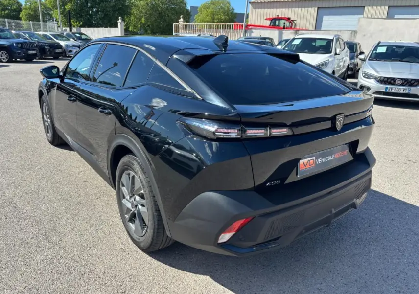 Vue 3/4 arrière droite d'une Peugeot 408 Hybrid noire, avec jantes alliage 19 pouces et vitres teintées.
