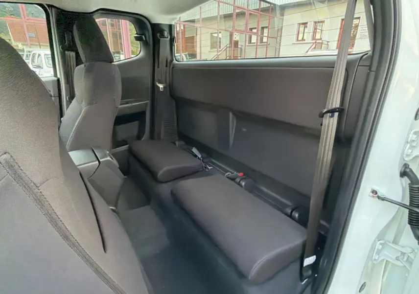 Vue intérieure côté droit du pick-up Isuzu D-MAX 2026 Splash White, montrant les sièges arrière rabattus en tissu noir.