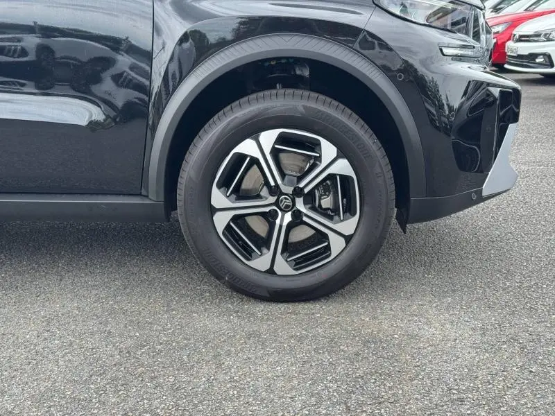 Gros plan sur la roue avant gauche d'une Citroën C3 Aircross 2026 noir Perla Nera avec jante alu bicolore.