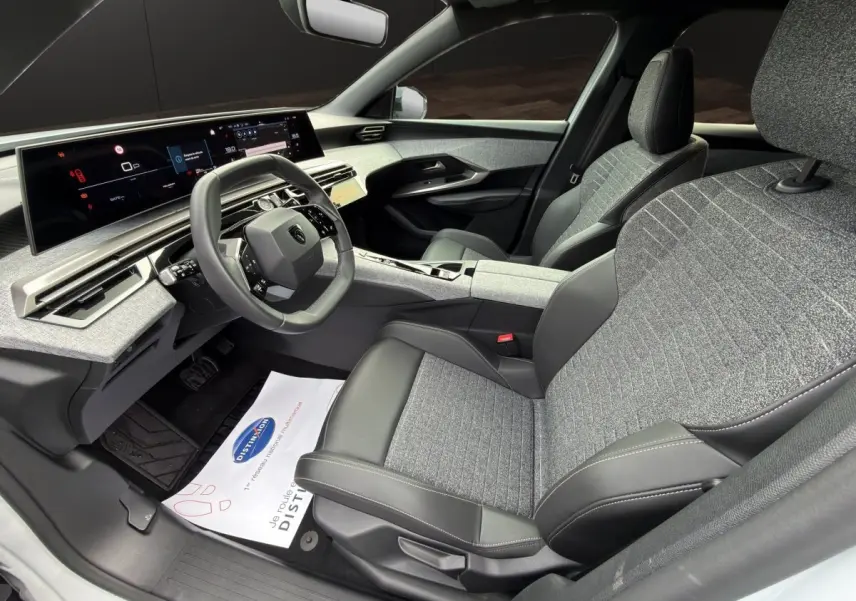 Vue intérieure côté conducteur du Peugeot 3008 2025, montrant les sièges gris et noir, le volant cuir multifonctions et l'écran tactile panoramique.