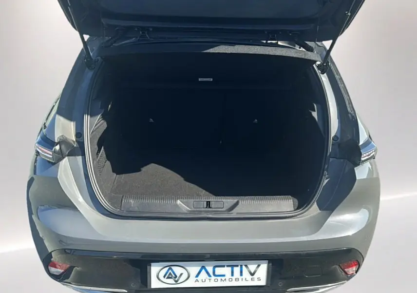 Vue arrière ouverte d'un Peugeot 308 gris 2025, coffre spacieux et feux arrière LED visibles.