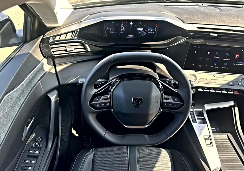 Vue intérieure centrée sur le volant multifonction et le tableau de bord numérique de la Peugeot 308 gris 2025.