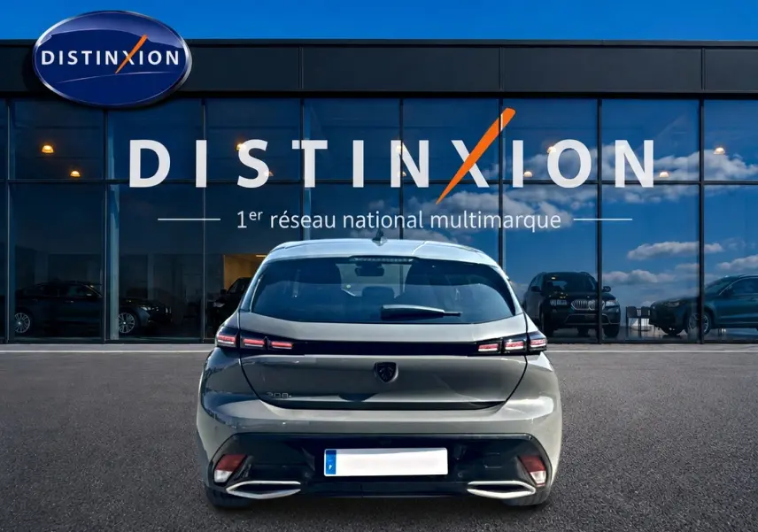 Vue arrière d'une Peugeot 308 gris métallisé garée devant une vitrine avec logo Distinxion.