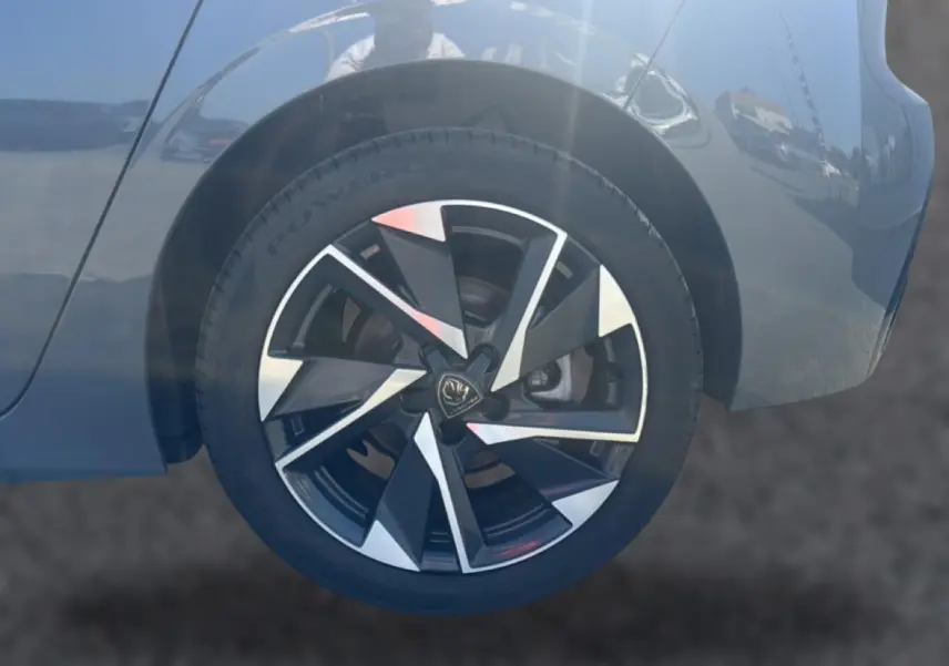 Gros plan sur la roue avant droite d'une Peugeot 308 gris métallisé avec jante alliage au design moderne.