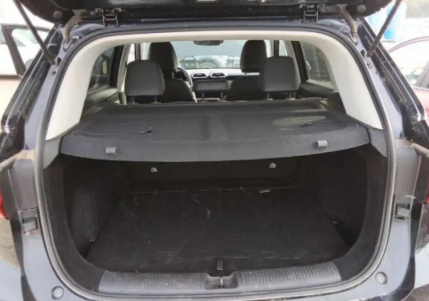 Vue arrière du coffre ouvert du MG MOTOR ZS 1.5 Hybrid+ 197 Luxury noir, avec cache-bagages en place.