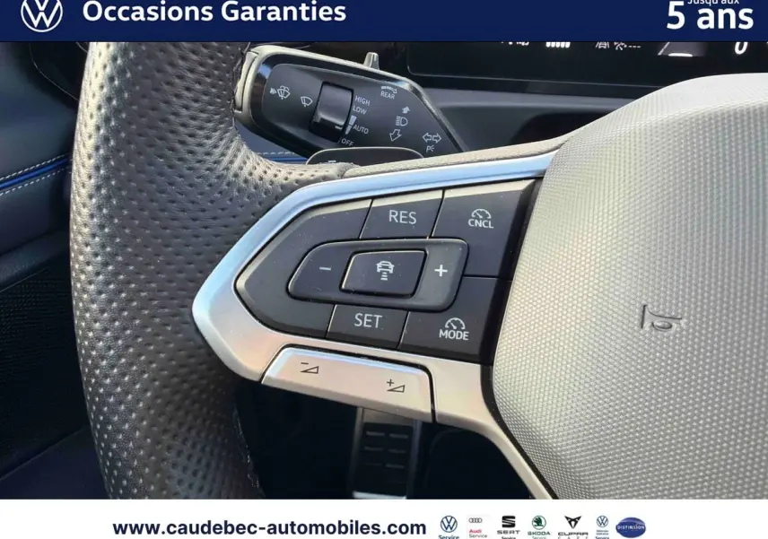 Gros plan sur le volant cuir perforé du Volkswagen Tiguan eHybrid 2025 avec commandes multifonctions et finition argentée.