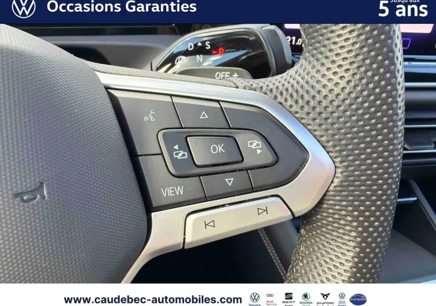 Gros plan sur les commandes multifonctions du volant en cuir perforé du Volkswagen Tiguan argent Dolomite 2025.