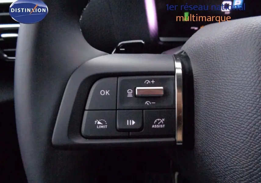 Gros plan sur les commandes au volant côté gauche du Citroën C4 X rouge Elixir Metal, mettant en valeur les boutons de régulateur et limiteur.