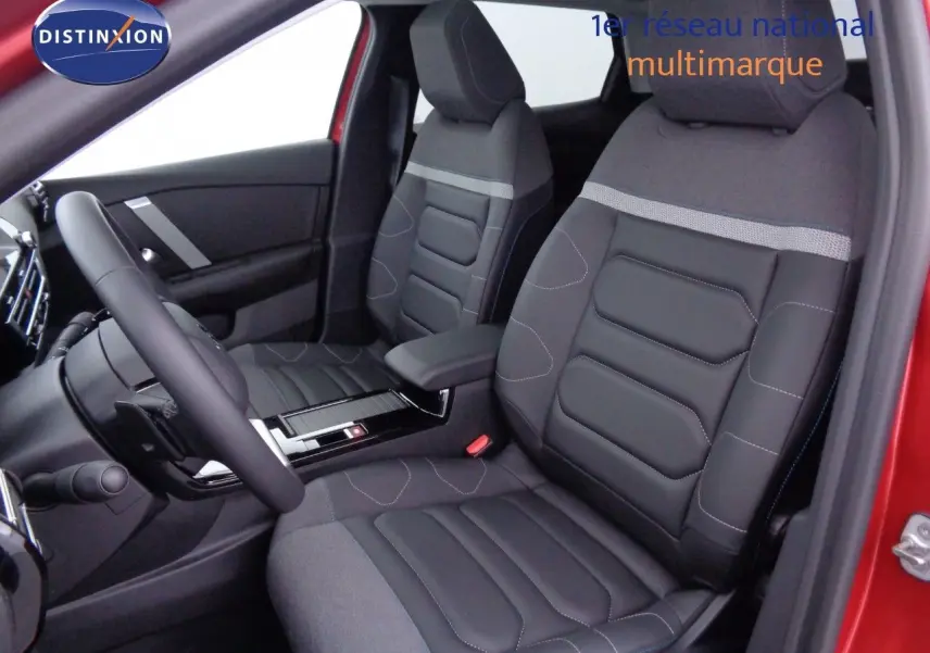 Vue intérieure côté conducteur de la Citroën C4 X rouge Elixir, sièges noirs en cuir et tissu avec console centrale visible.
