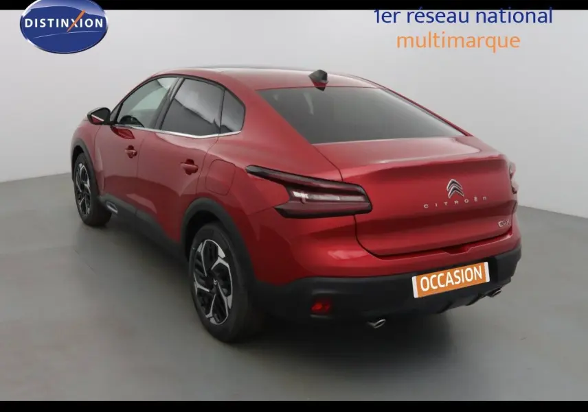 Vue 3/4 arrière droite d'une Citroën C4 X rouge Elixir métal avec feux arrière LED et jantes bi-ton.