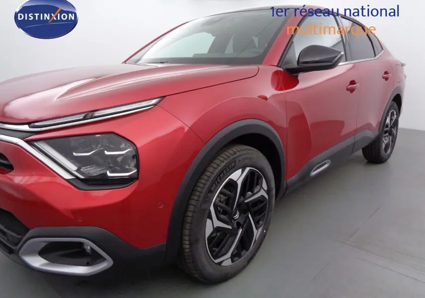 Vue 3/4 avant droit d'une Citroën C4 X rouge Elixir Métal avec jantes alliage bicolores et détails noirs contrastants.