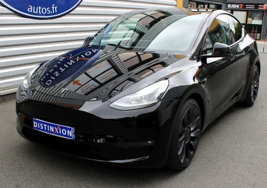 Tesla Model Y Performance noir métal vue 3/4 avant droit, roues noires et surface brillante réfléchissante.