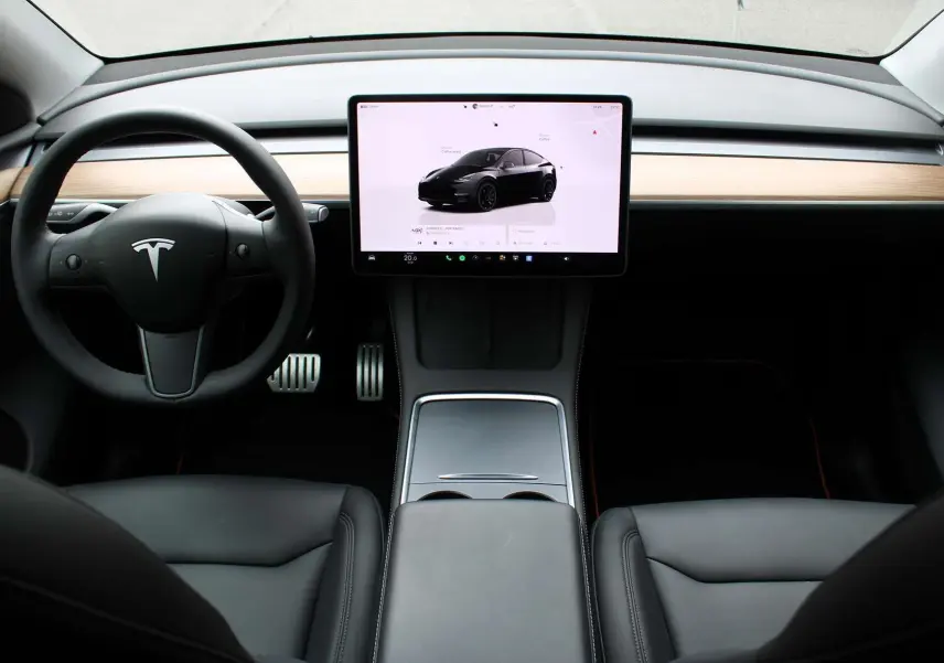 Intérieur avant de la Tesla Model Y Performance 2024 noir métal, tableau de bord minimaliste avec grand écran tactile central.
