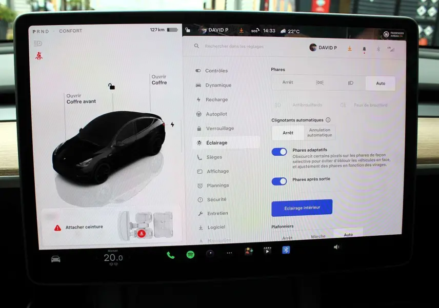 Écran tactile central d'une Tesla Model Y noir métal 2024 montrant les réglages d'éclairage et l'interface du véhicule.