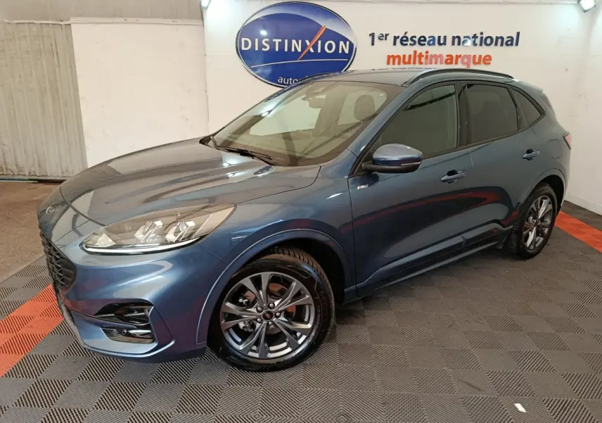 Ford Kuga bleu en vue 3/4 avant droit, avec jantes alliage et toit noir dans un showroom intérieur.
