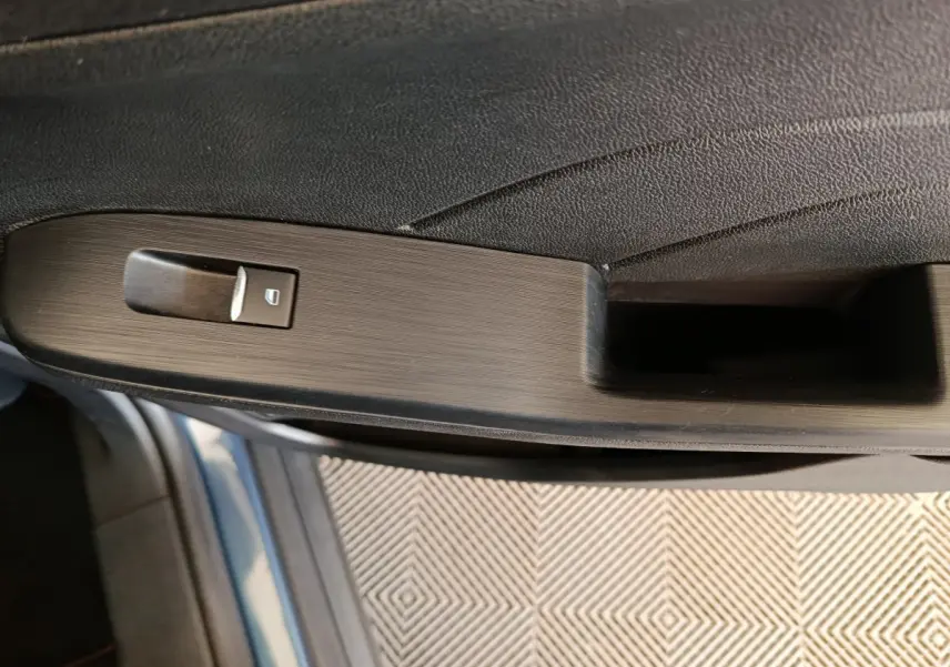 Gros plan sur la poignée intérieure côté gauche du Ford Kuga bleu 2024 avec bouton de verrouillage intégré.