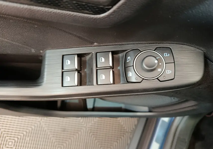 Gros plan sur les commandes des vitres et rétroviseurs côté conducteur du Ford Kuga bleu 2024 St Line.