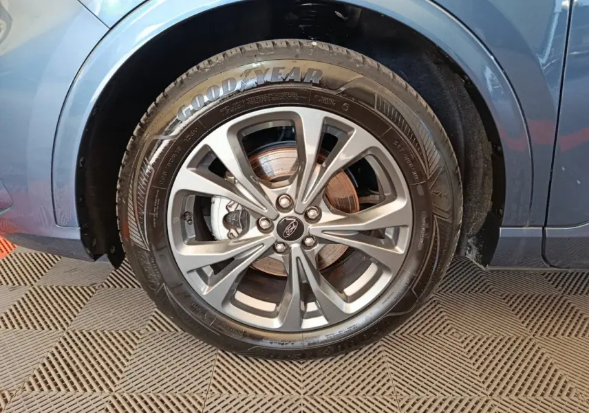 Gros plan sur la roue avant gauche du Ford Kuga bleu 2024, avec jante alliage et pneu Goodyear visible.