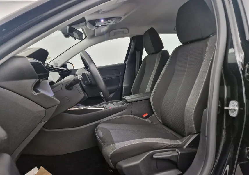 Vue intérieure centrée sur le volant cuir et le tableau de bord numérique de la Peugeot 308 noire de 2022.