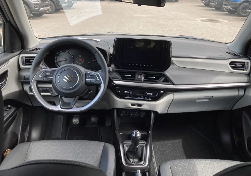 Vue intérieure avant de la Suzuki Swift 1.2 Dualjet Hybrid Allgrip Pack 2025, volant cuir multifonctions et boîte manuelle.