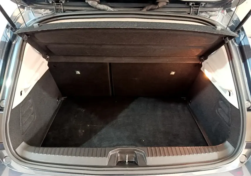 Coffre ouvert de Renault Clio gris foncé, vue arrière montrant l’espace de chargement vide et la tablette de séparation.