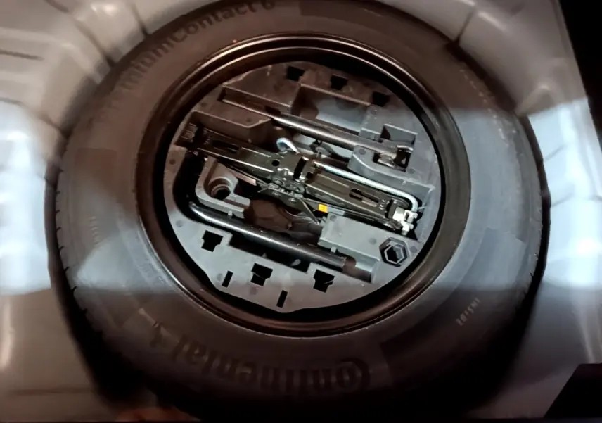 Gros plan sur la roue de secours et les outils de bord dans le coffre d’une Renault Clio gris foncé 2022.