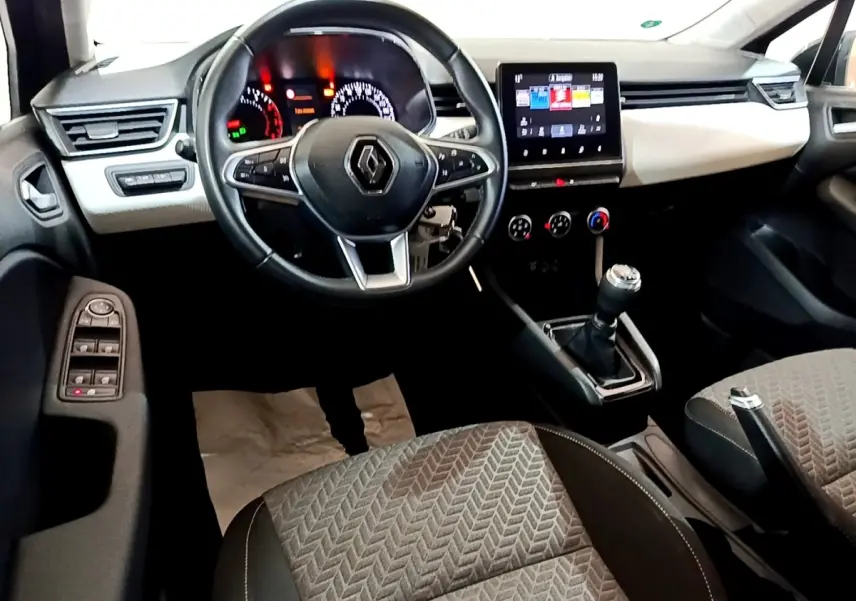 Vue intérieure avant de la Renault Clio gris foncé 2022, volant multifonctions, écran tactile central et boîte manuelle.