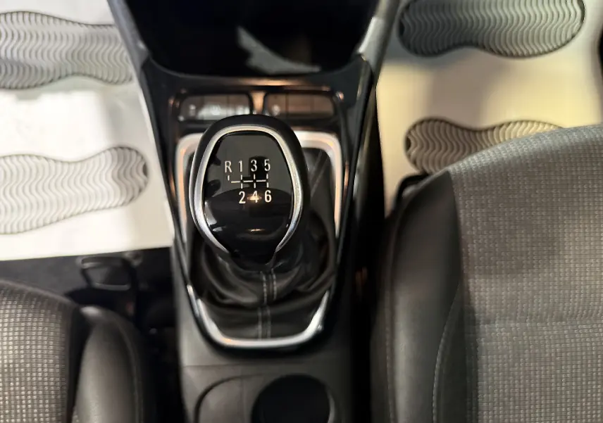 Vue plongeante sur le levier de vitesses manuel noir de l’Opel Crossland rouge, entouré des sièges avant.