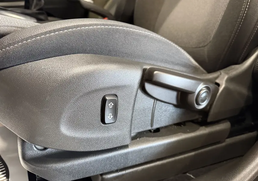 Gros plan sur la commande de réglage manuel du siège avant en tissu gris de l’Opel Crossland 2022.