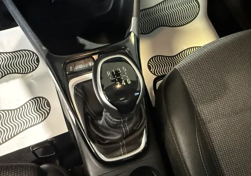 Gros plan sur le levier de vitesse manuel entouré de cuir noir dans l’habitacle de l’Opel Crossland rouge.