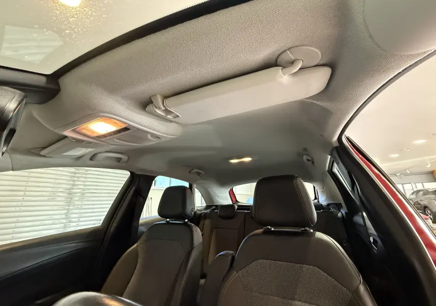 Vue intérieure de l'Opel Crossland rouge montrant les sièges avant et arrière avec toit clair et pare-soleil.