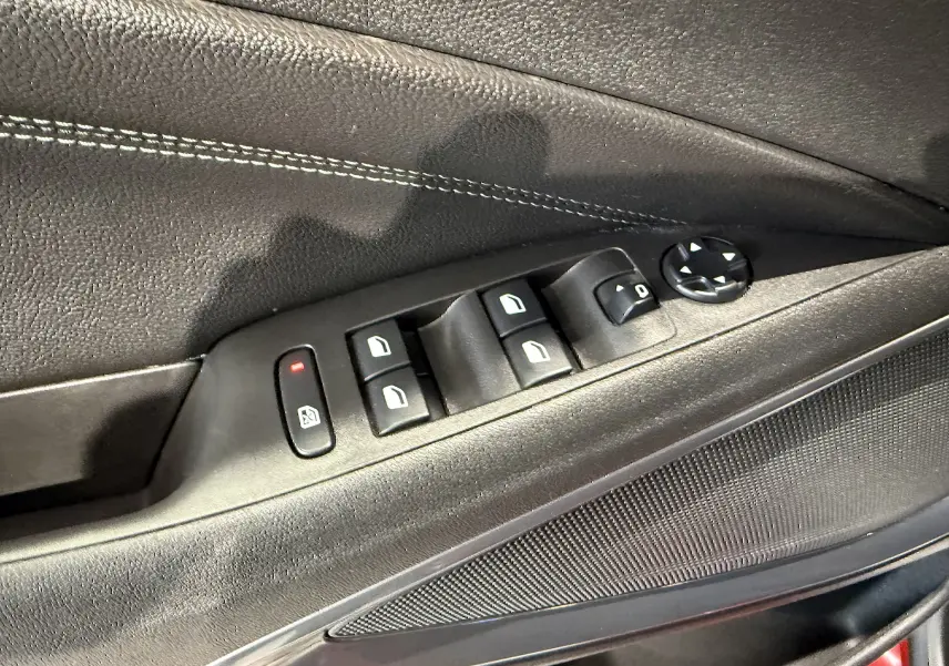 Détail des commandes des vitres électriques sur la porte côté gauche d'une Opel Crossland rouge 2022.
