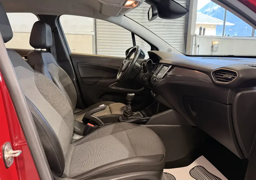 Vue intérieure côté gauche de l’Opel Crossland rouge 2022, montrant les sièges tissu et la boîte manuelle.