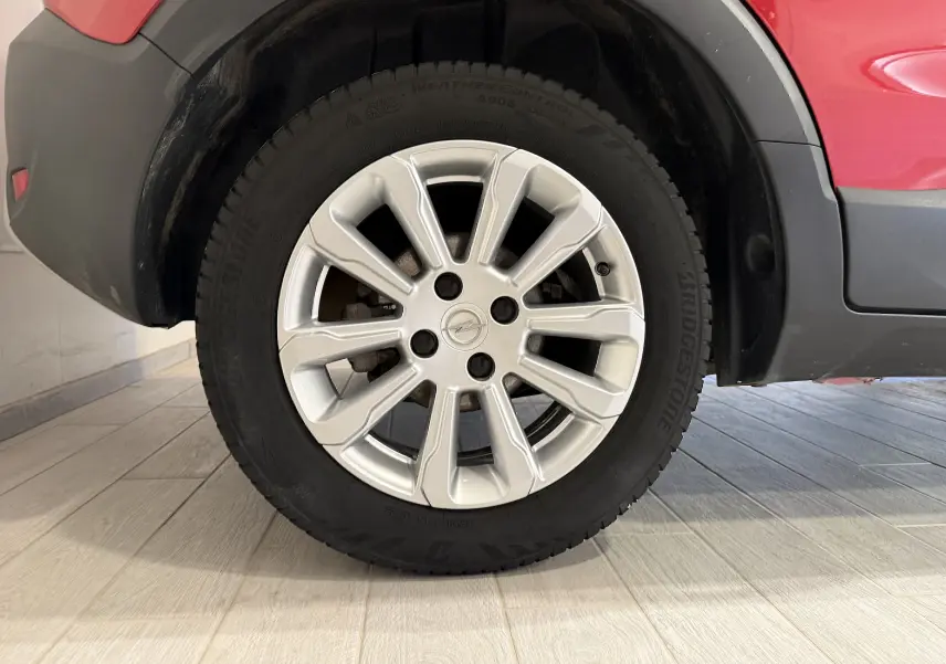 Gros plan sur la roue avant gauche de l’Opel Crossland rouge, mettant en valeur la jante argentée et le pneu Bridgestone.