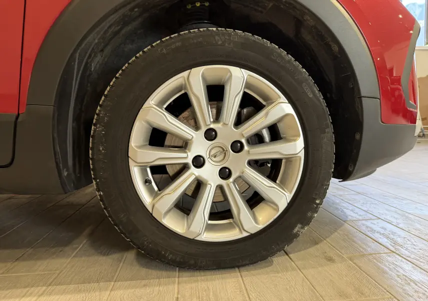 Gros plan sur la roue avant droite d’un Opel Crossland rouge 2022, mettant en valeur la jante alliage argentée.