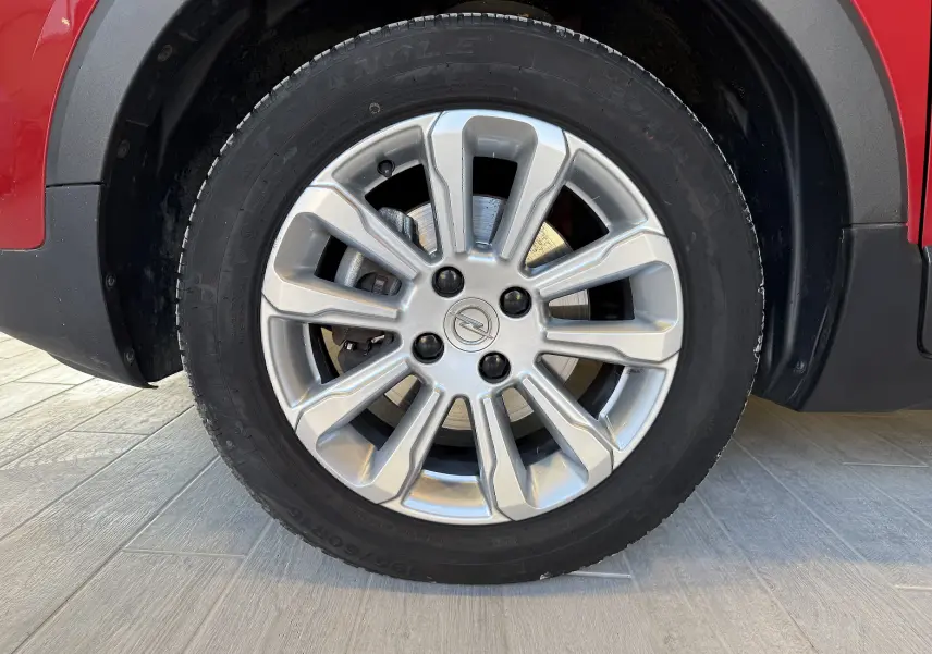 Gros plan sur la roue avant droite avec jante argentée de l’Opel Crossland rouge 2022.